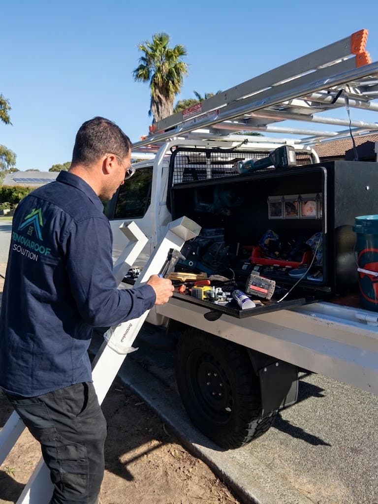 Renovaroof Solution roofer at the open tool drawer of the work ute, ladders racked above, a length of guttering in hand